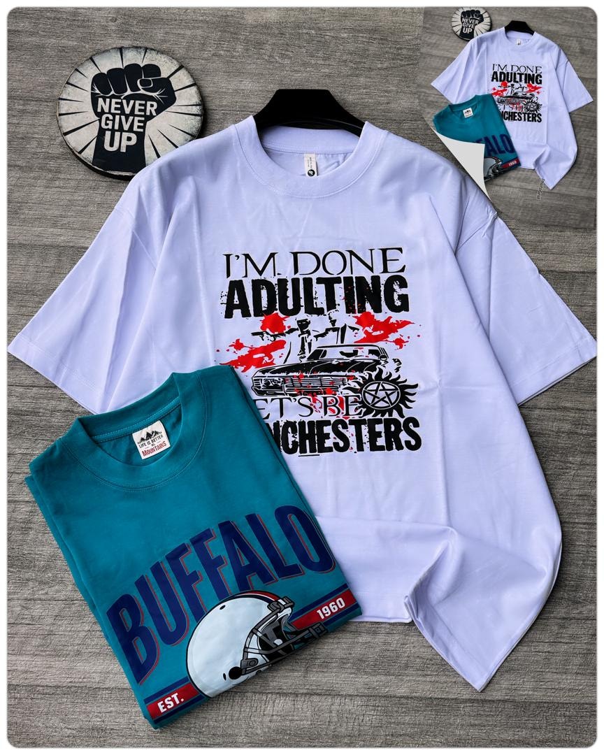 White oversized t-shirt with I'm Done Adulting car graphic on hanger with folded teal Buffalo tee.