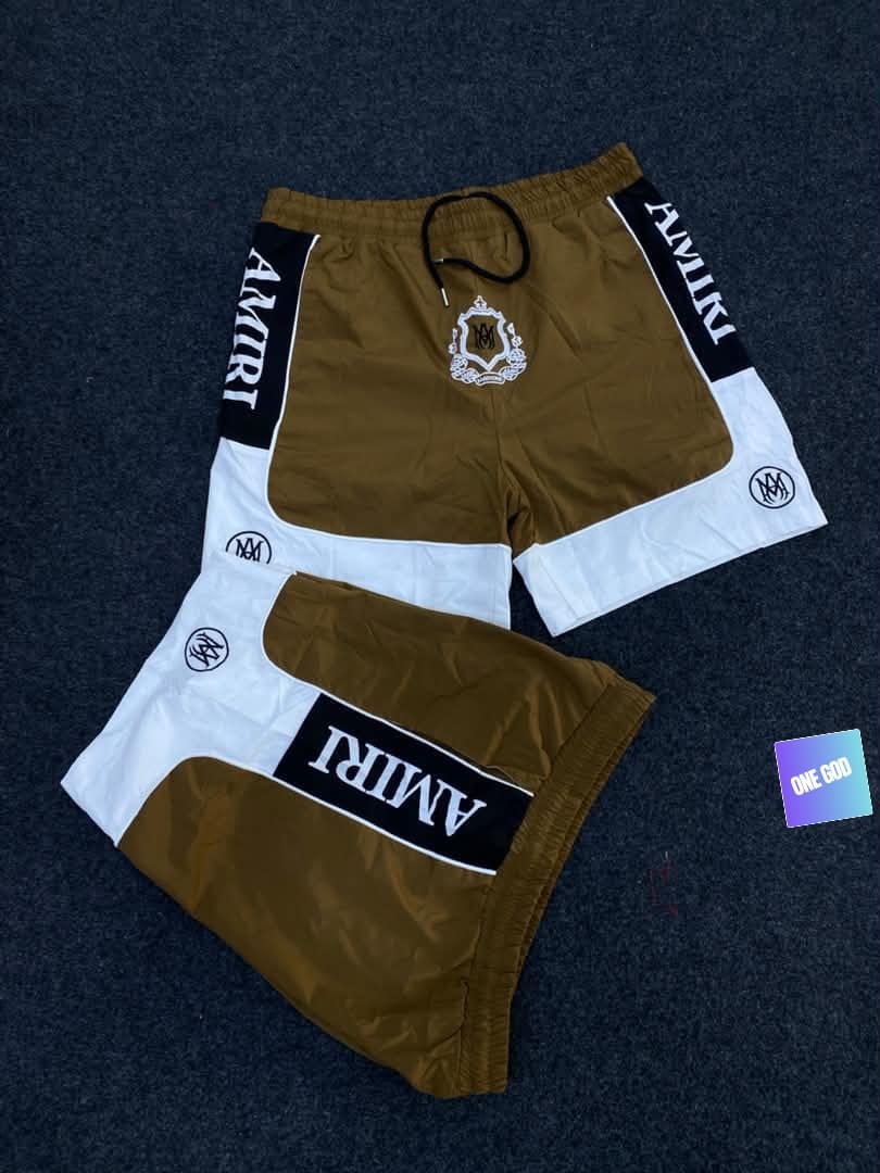 Brown and white Amiri logo colorblock shorts with crest emblem.