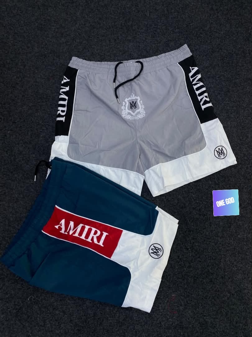 Gray and teal Amiri logo colorblock shorts with branding details.