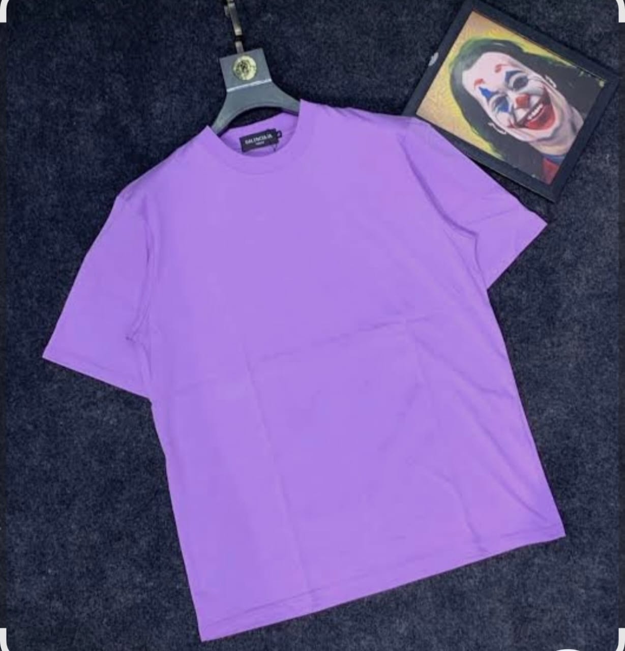 Purple plain t-shirt laid flat on dark surface with artwork in background.