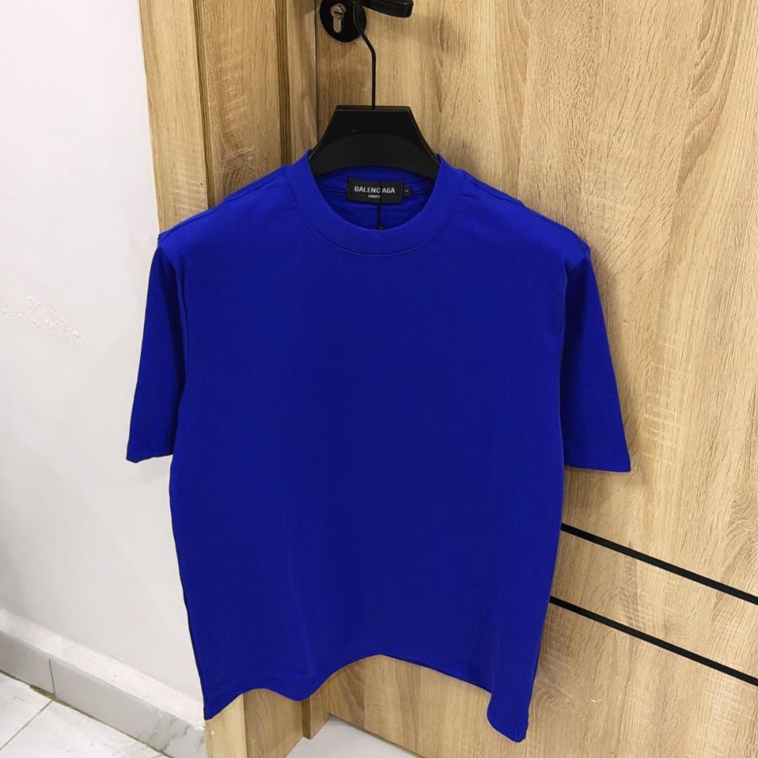 Blue plain oversized t-shirt on black hanger against wooden background.