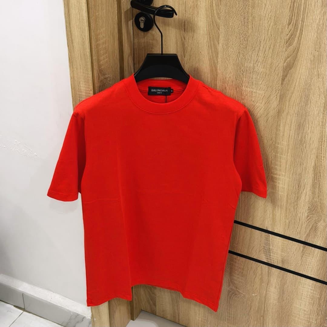 Red plain oversized unisex t-shirt hanging on a door.
