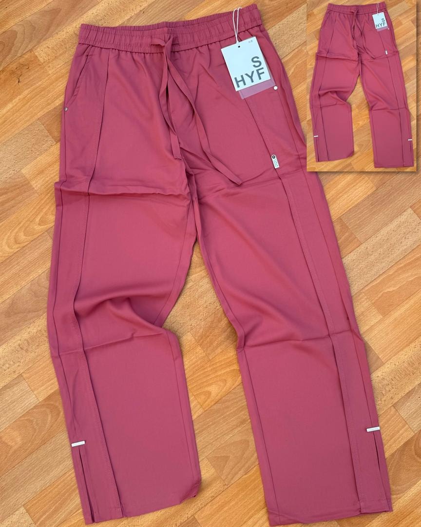 Burgundy HYF material joggers laid flat on wooden floor with inset detail and size tag.