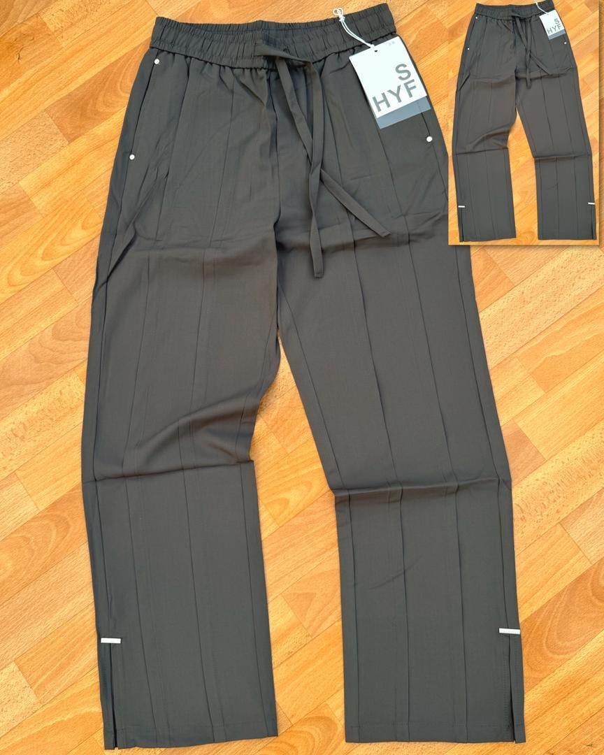 Gray HYF material joggers laid flat on wooden floor with inset detail and size tag.