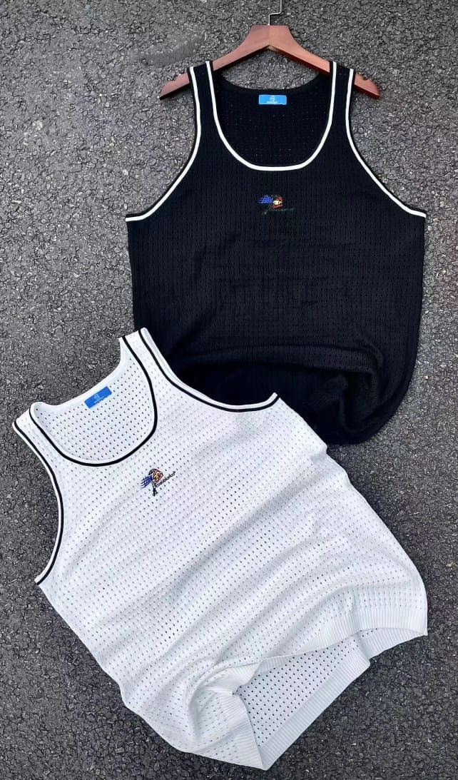 Black and white perforated mesh armless tank tops with contrast white trim and chest embroidery laid on pavement