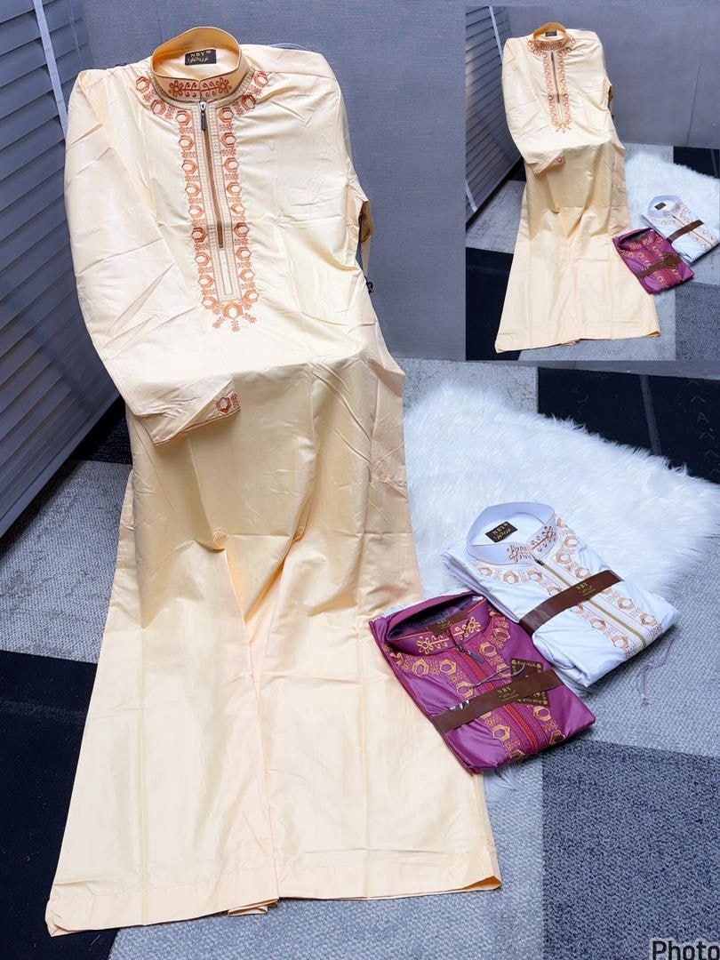 Cream jalamia with orange circular embroidery and folded purple and white versions on white rug.