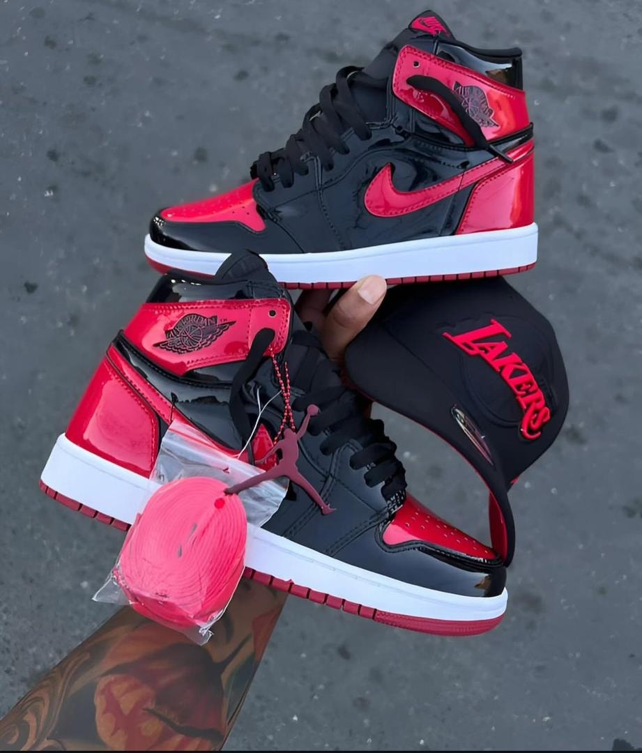 Black and red Air Jordan 1 high-top sneakers held with Lakers cap and extra red laces.
