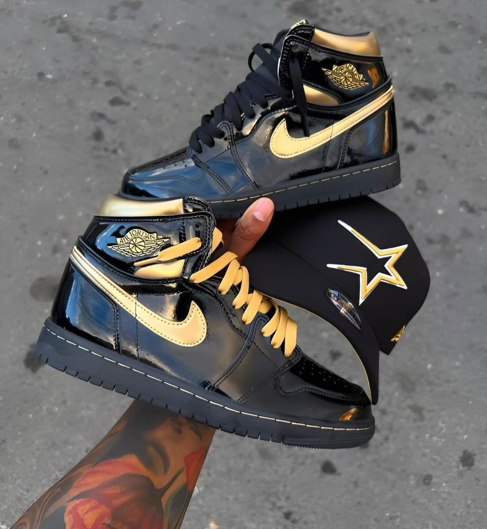 Black and gold patent Air Jordan 1 high-top sneakers held with a black cap featuring gold star logo.