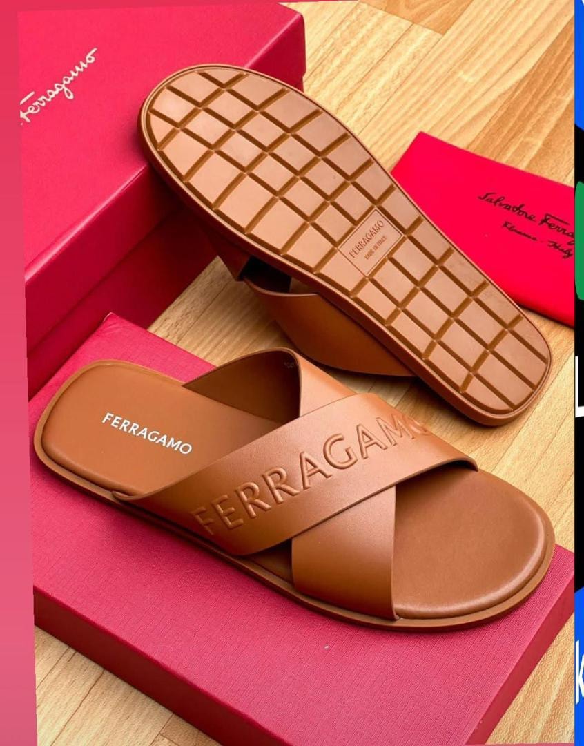 Brown Ferragamo cross-strap slides shown on red branded boxes with detailed sole view.
