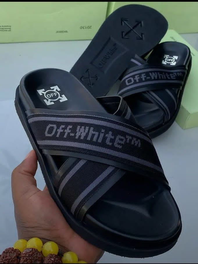 Black Off-White slides with arrow logos and text held in hand showing detailed branding.