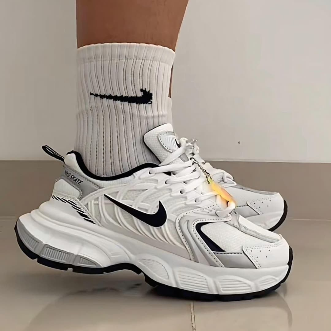 White Nike TC 7900 sneakers worn with white Nike socks on a tiled floor.