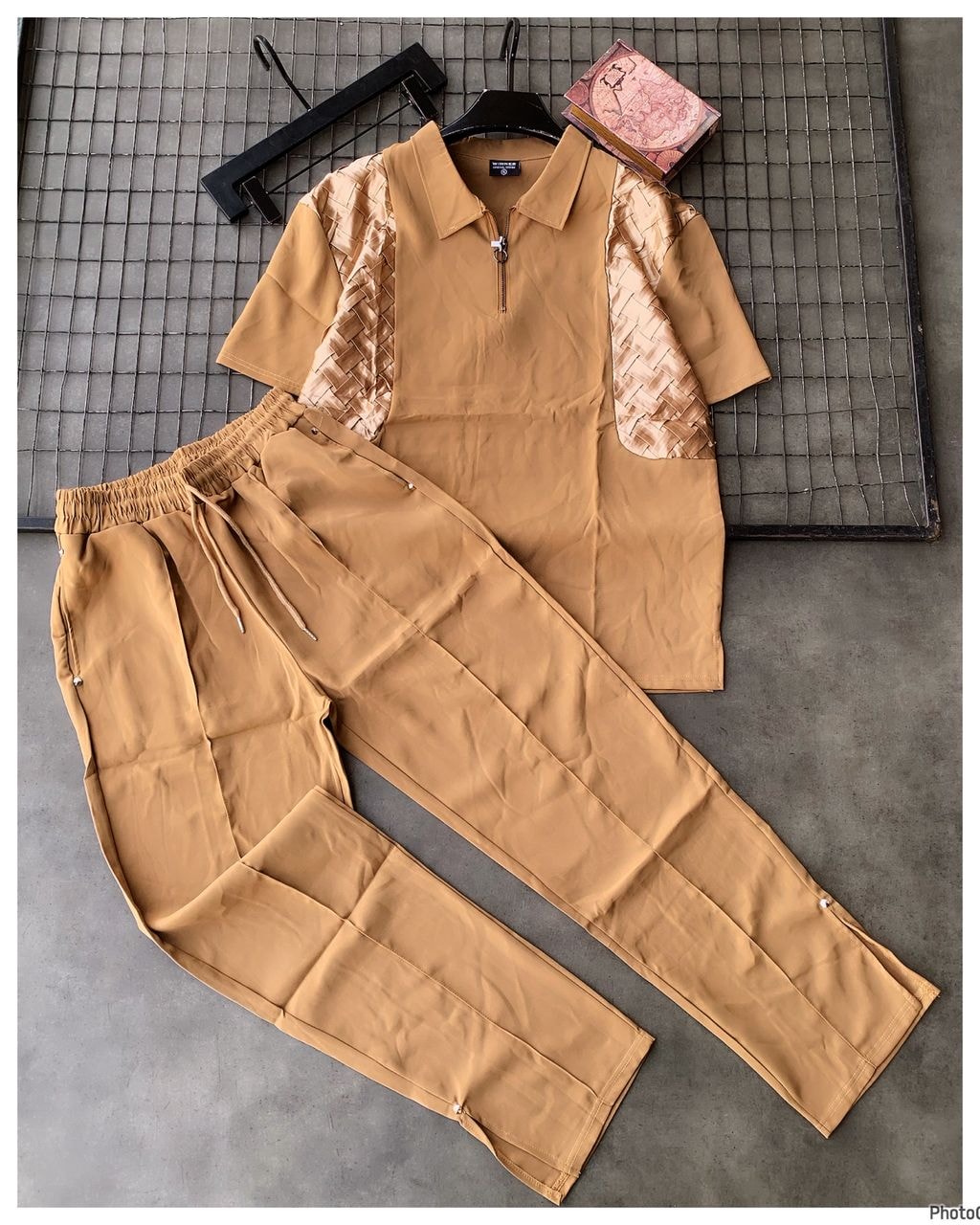 Camel unisex two-piece set with woven panel polo top and matching trousers laid flat.