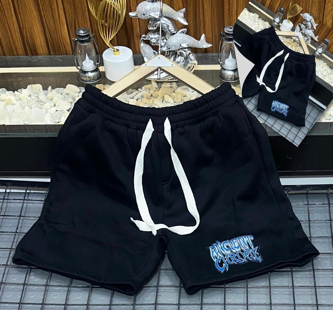 Black short joggers featuring Ancient Chrome embroidery on the left leg, displayed on a metal grid with decorative background.