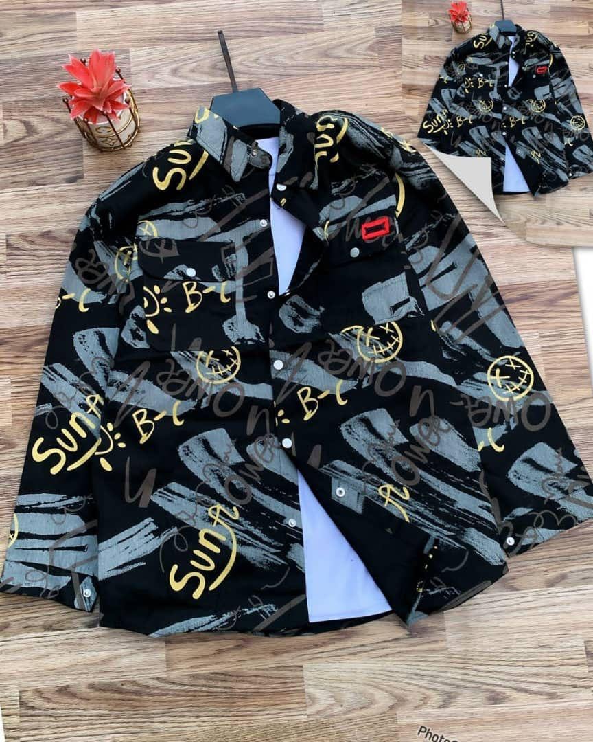 Black sun graffiti jacket displayed on wooden floor with yellow text and abstract patterns.