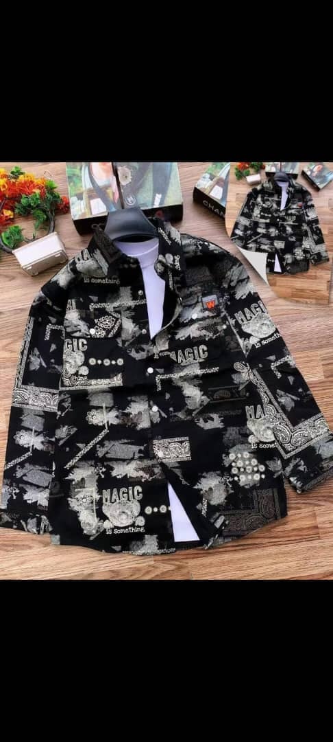Black magic print jacket laid flat on wooden floor showing all-over text and graphic details.