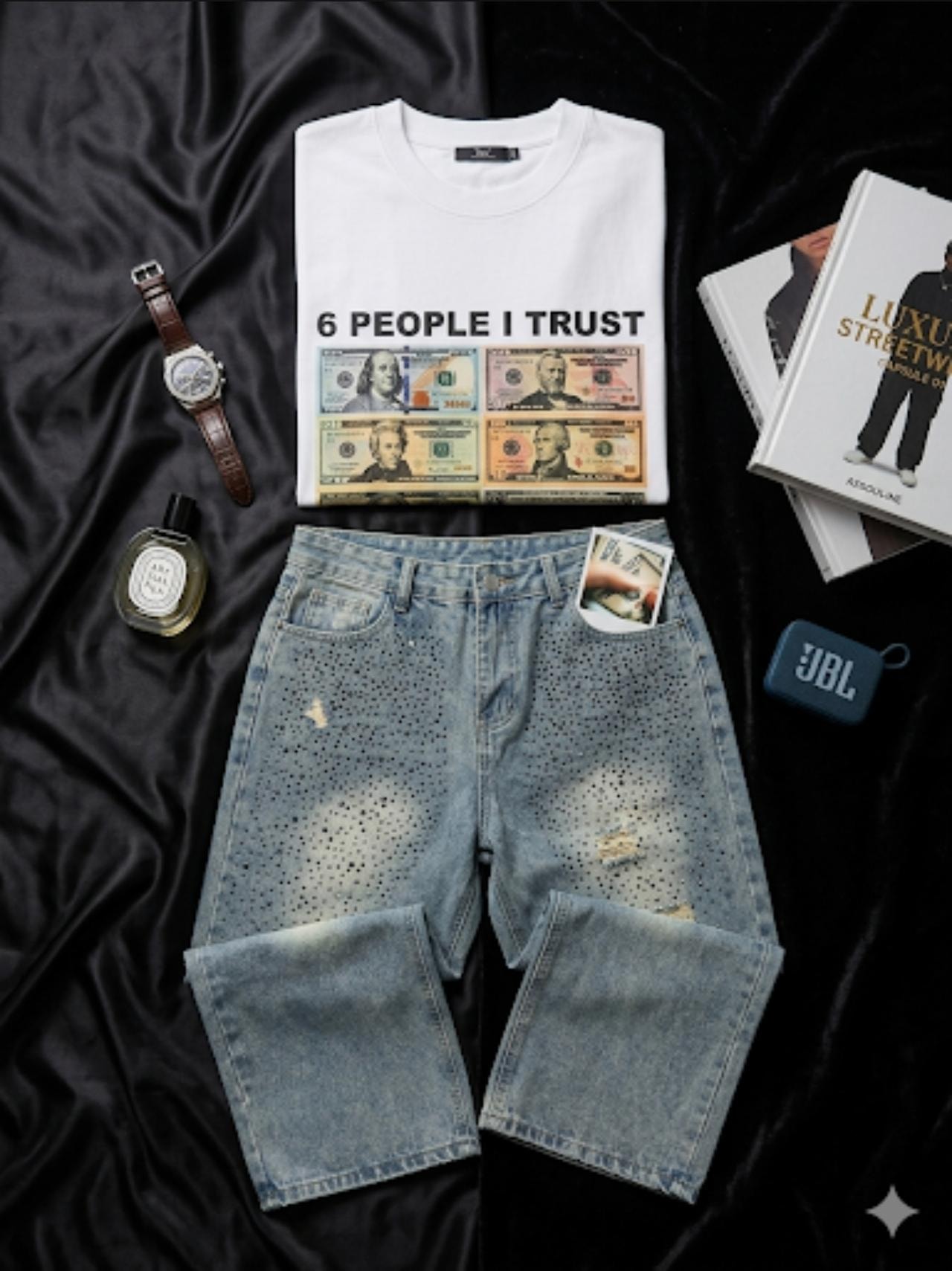 White 6 People I Trust money graphic t-shirt with light blue distressed denim shorts on black fabric.