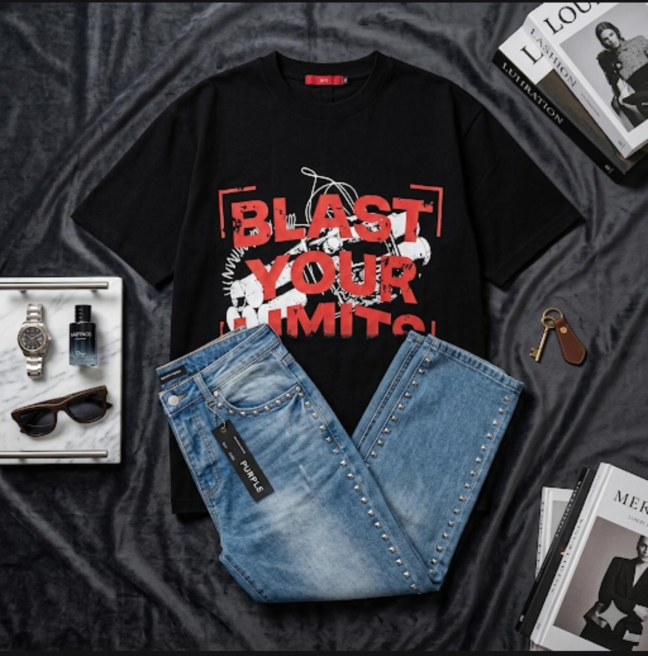 Black Blast Your Limits graphic t-shirt paired with blue studded jeans on dark background with accessories.