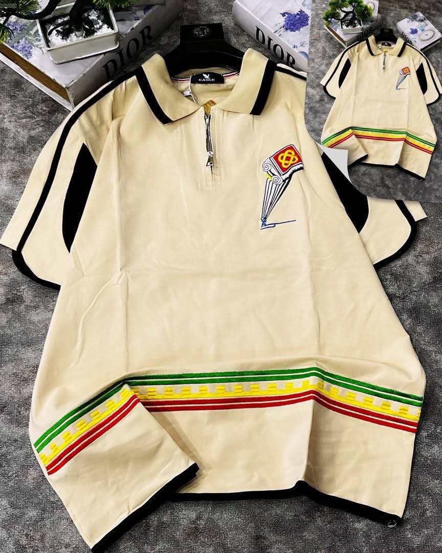 Cream striped hem polo shirt with colorful cuff and hem stripes plus chest emblem embroidery.