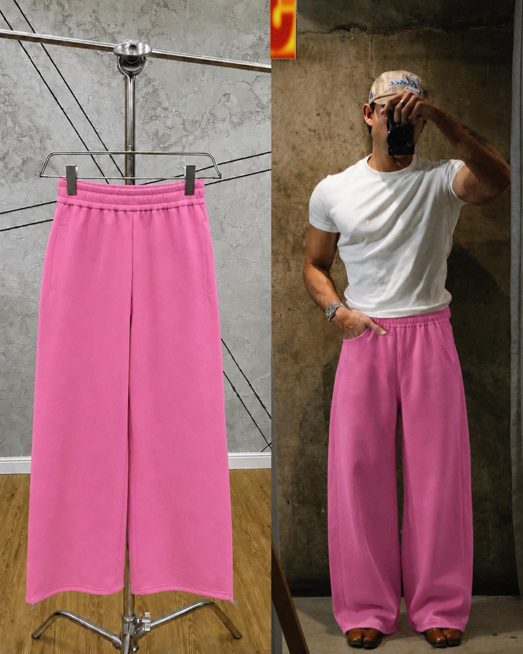 Pink unisex wide-leg joggers on hanger and model in studio