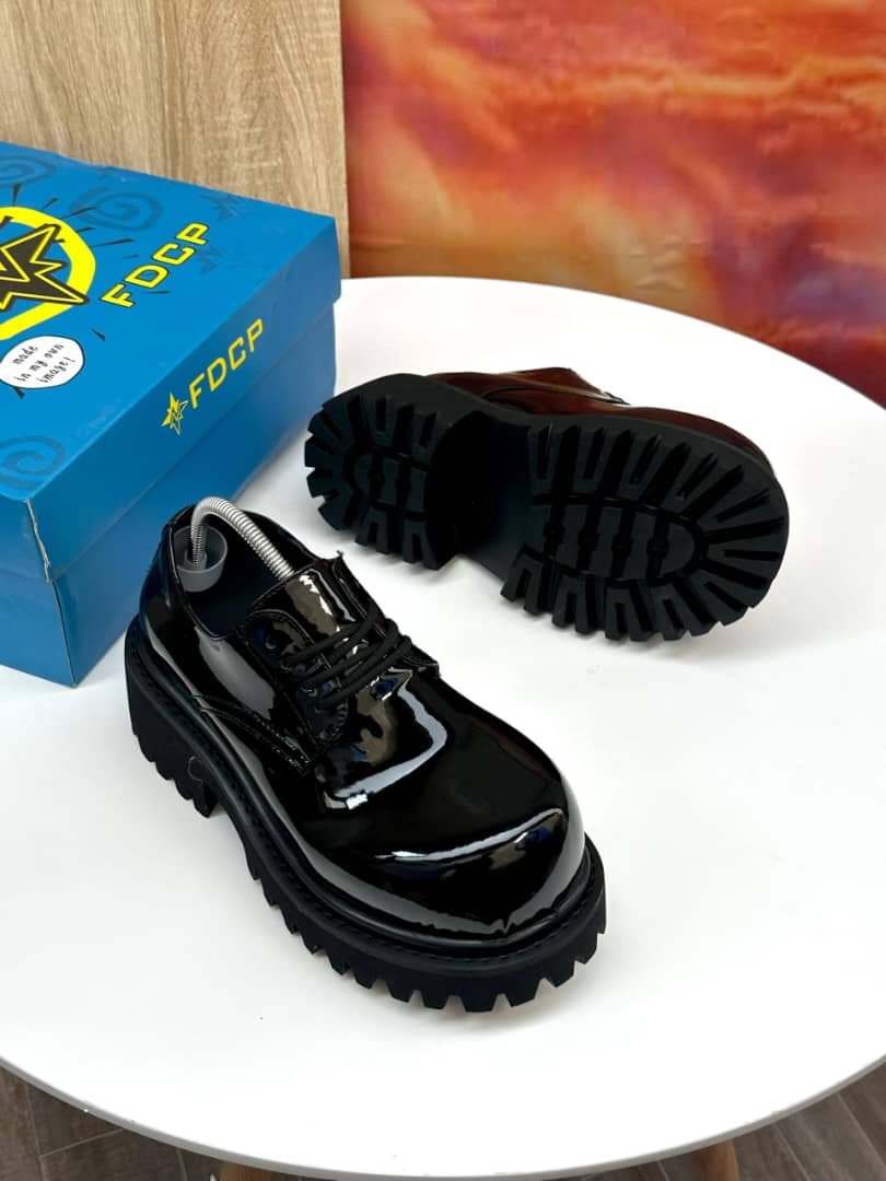 Black patent leather platform derby shoes with thick black lug sole and blue FDCP box.