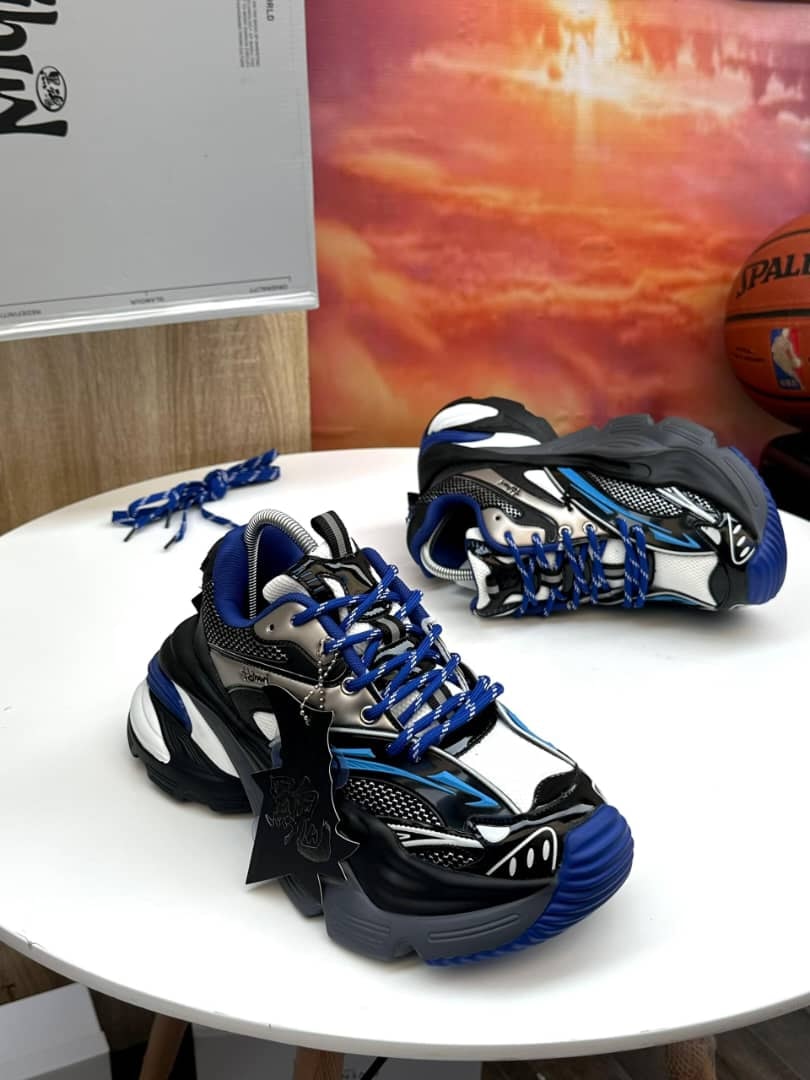 Black blue and white chunky sneakers on white table with accessories and sunset backdrop.