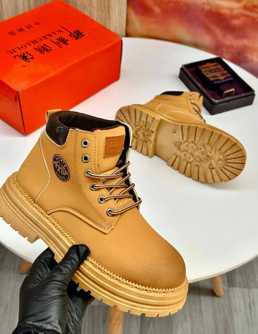 Mustard yellow combat boots held showing front and sole view with product boxes.
