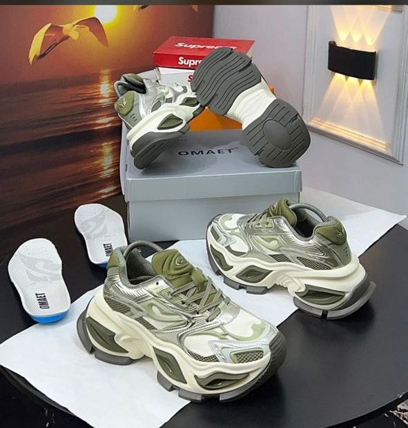 Green and silver chunky sneakers displayed with insoles shoebox and lifestyle backdrop.