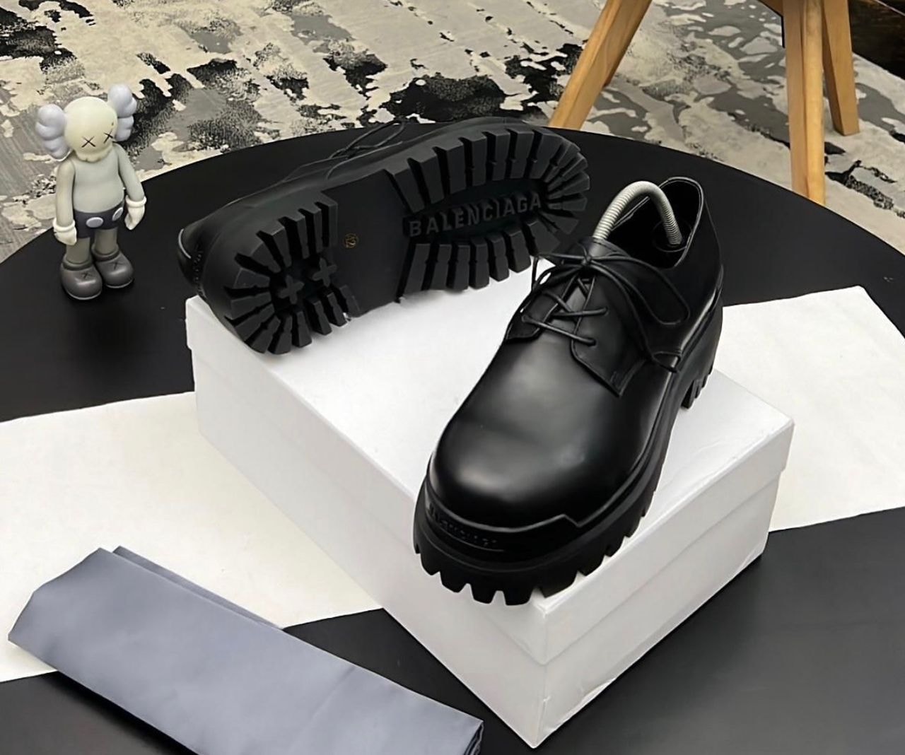 Black Balenciaga lug sole derby shoe on white box showing thick treaded sole.