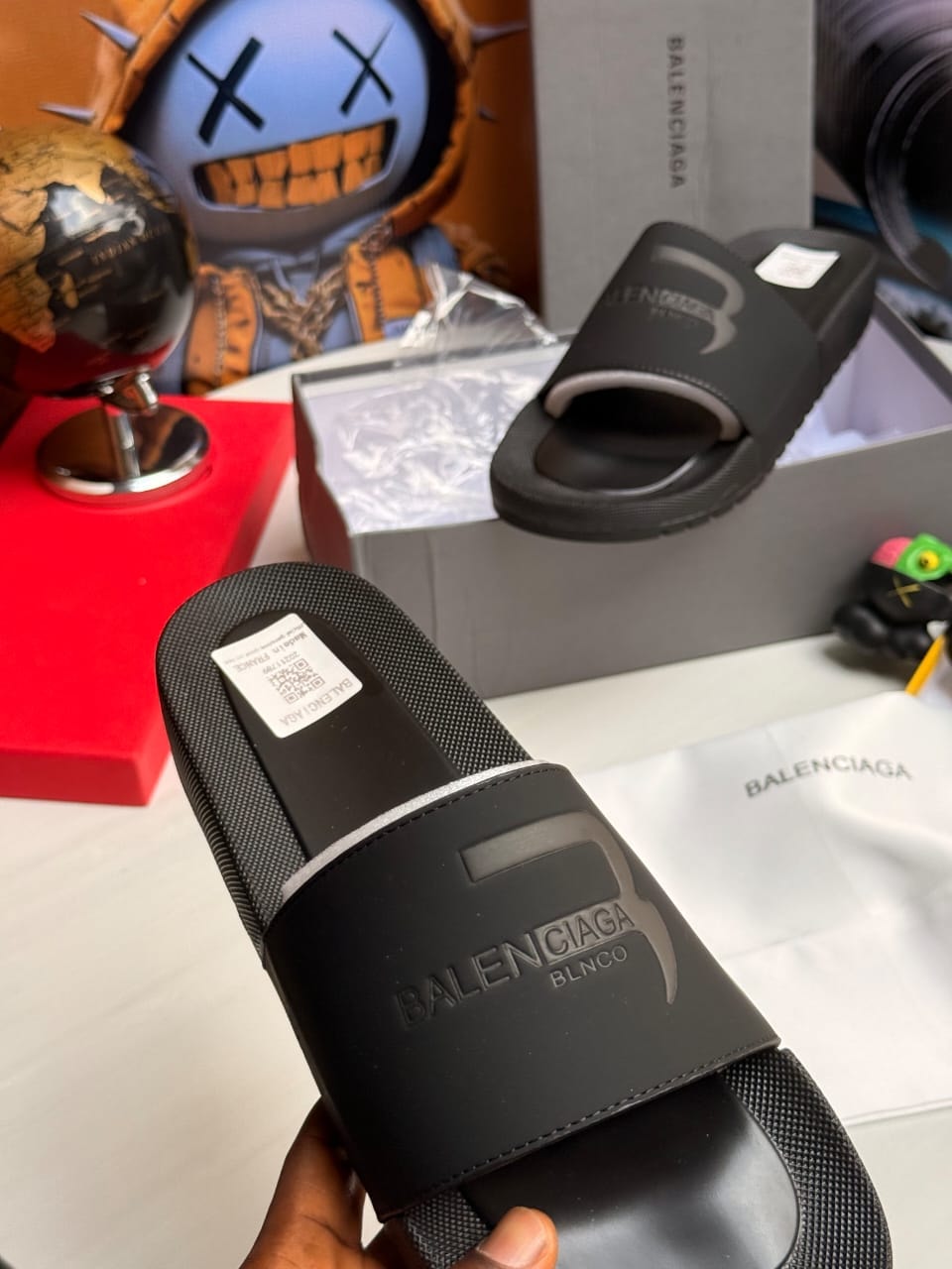 Black Balenciaga slides with embossed B logo and text.