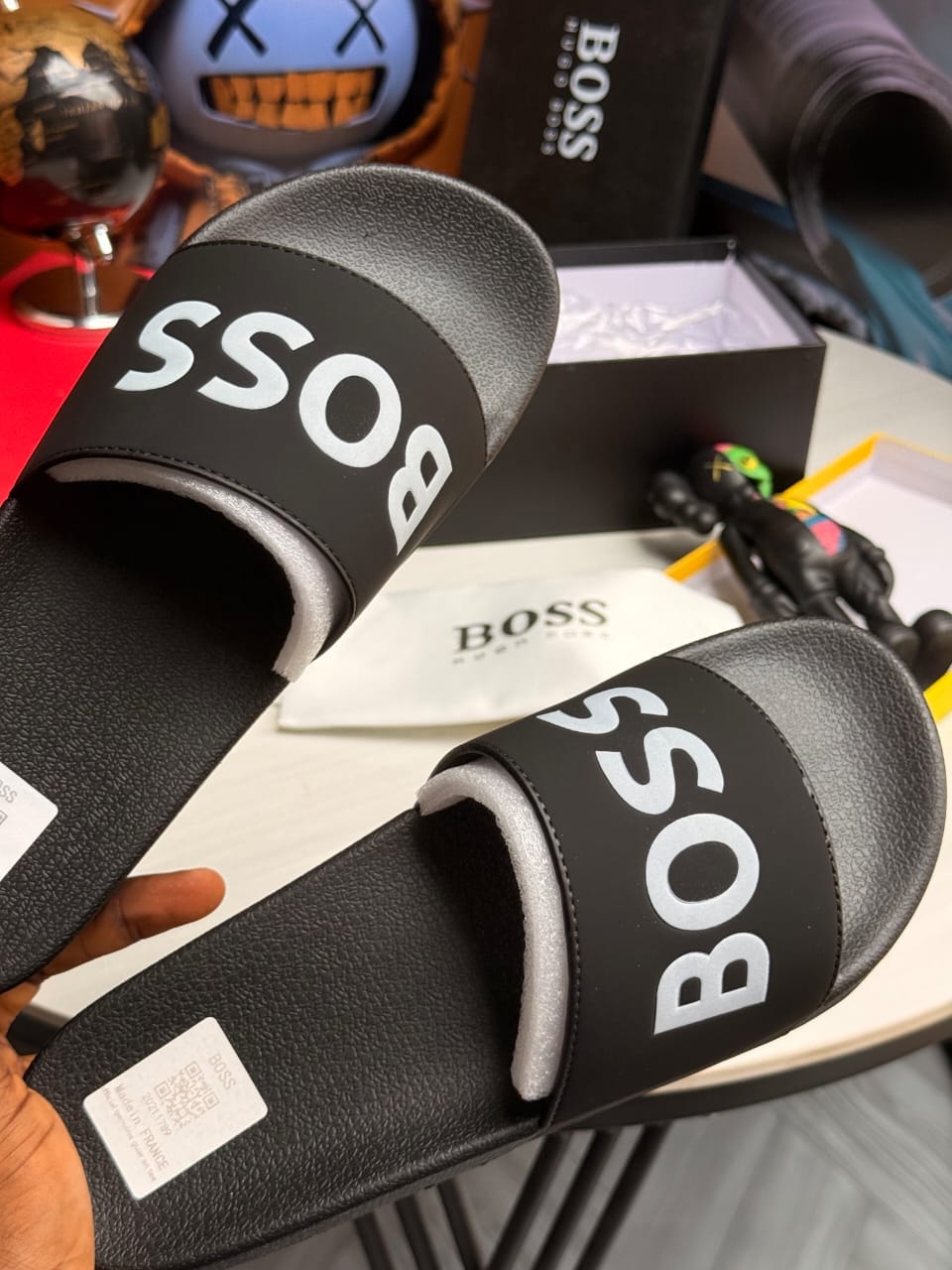 Pair of black Boss slides held showing bold white logo and details.