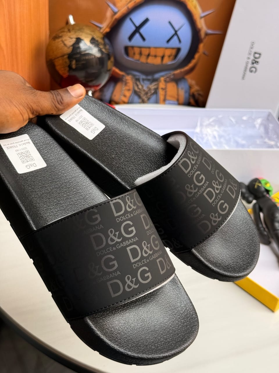 Pair of black D&G slides held displaying all-over logo pattern.