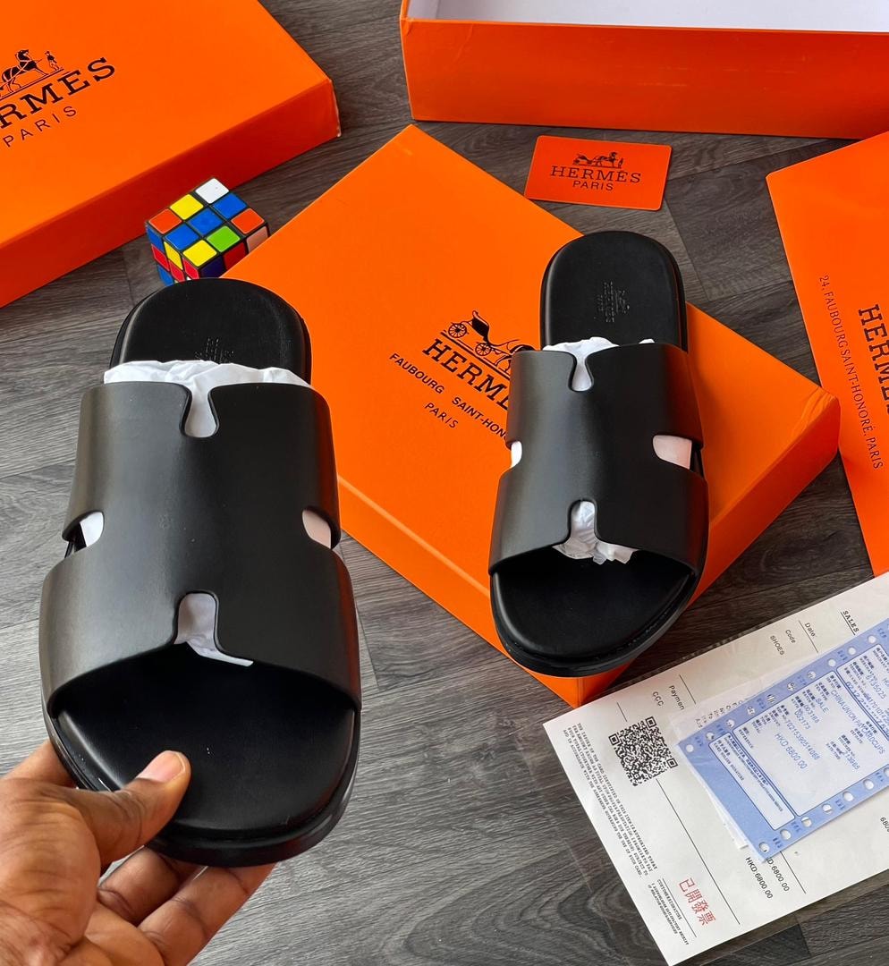 Black slides with orange Hermes boxes, cards and packaging on wooden surface.