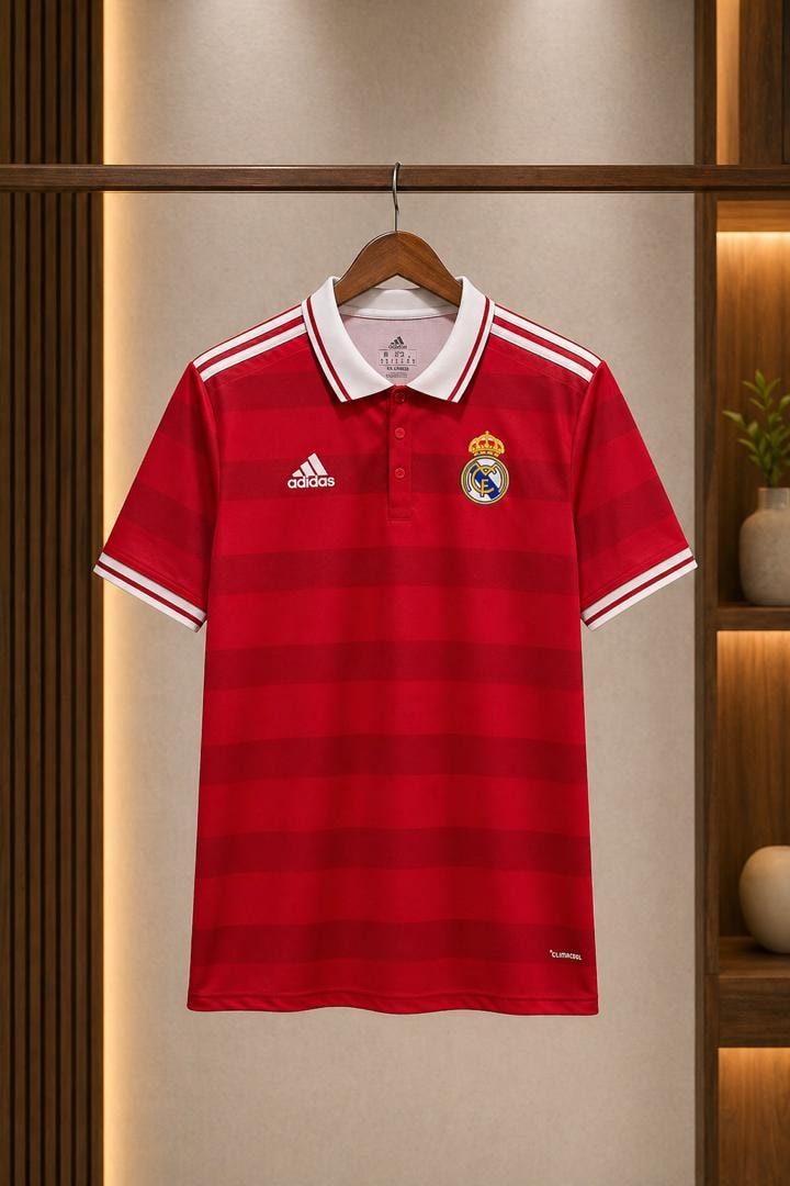 Red striped Real Madrid polo jersey hanging on wooden hanger in modern interior.