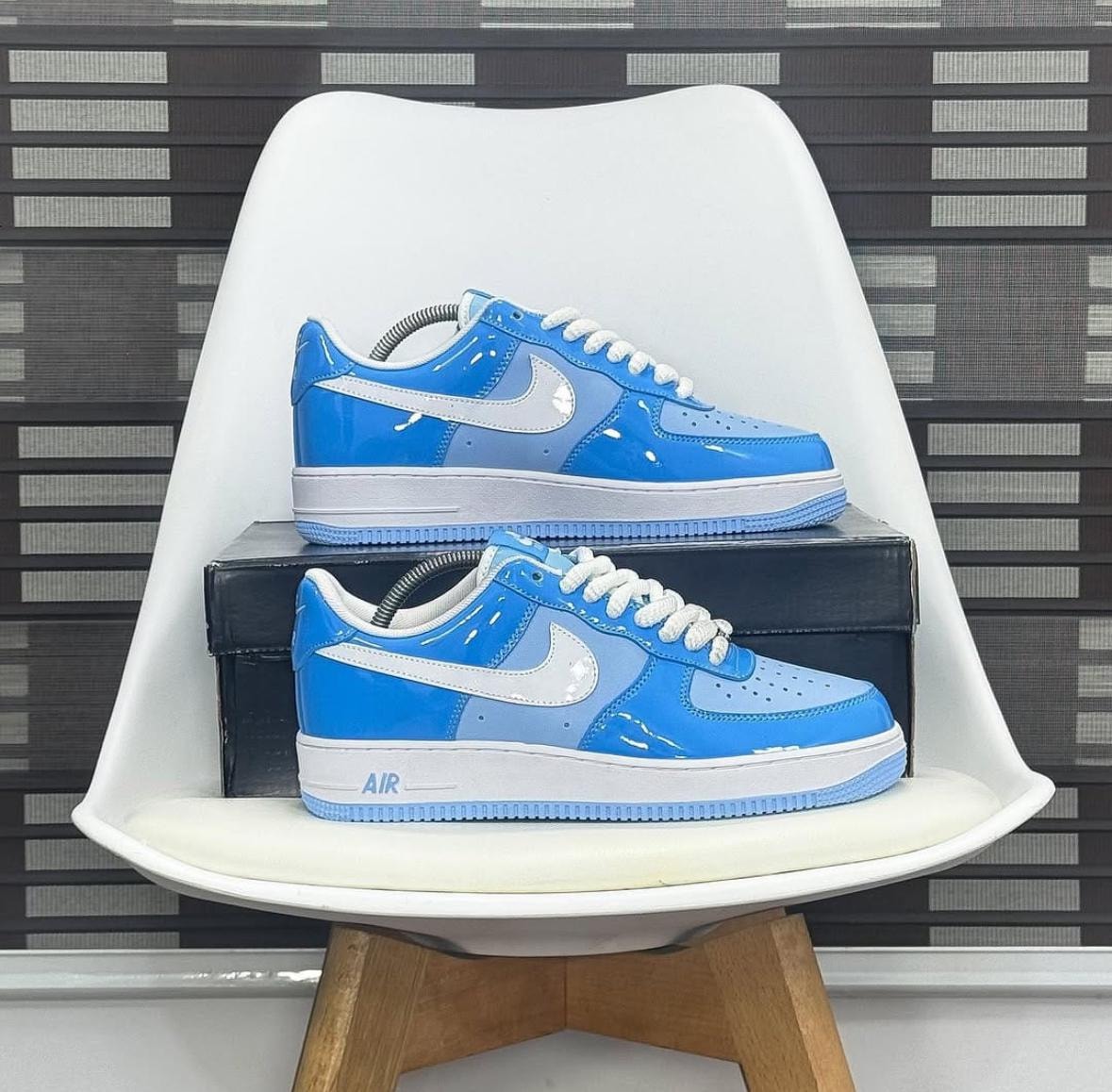 Blue and light blue paint splatter Air Force 1 sneakers on white chair.
