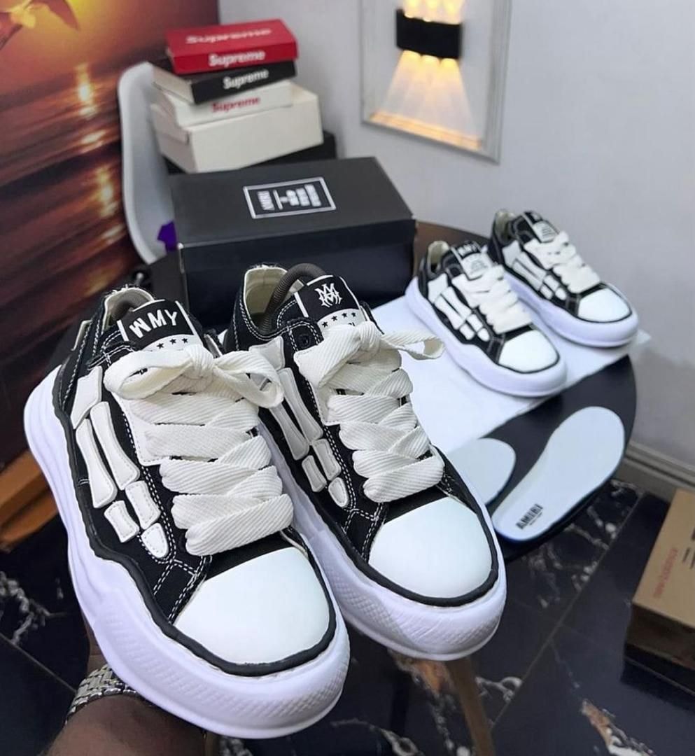 Black and white skeleton design sneakers held in hand with box in background.