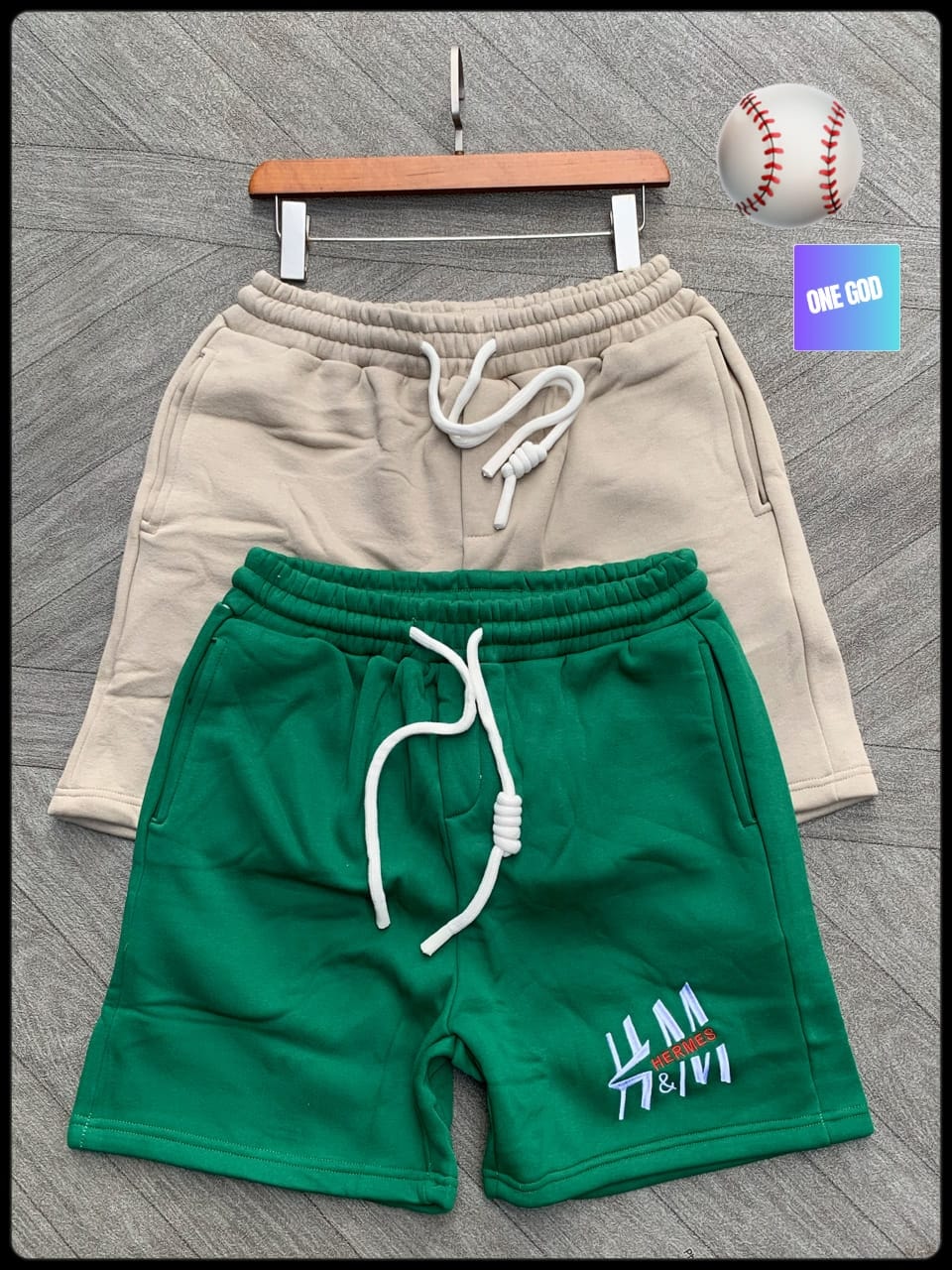 Green fleece shorts with Hermes embroidery and beige pair on gray surface.