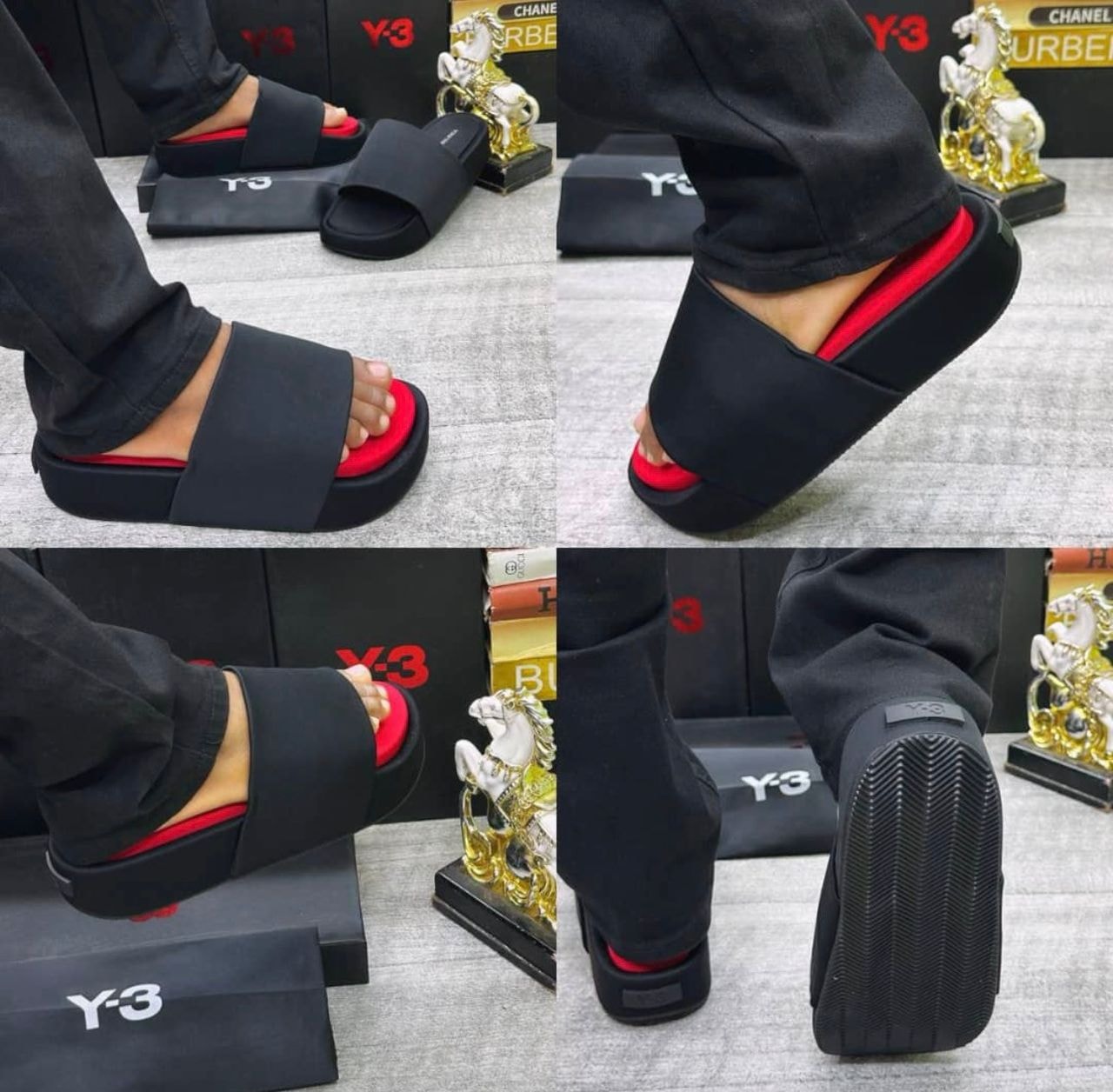 Black Y-3 slides with red insole shown on feet in lifestyle setting with product boxes.