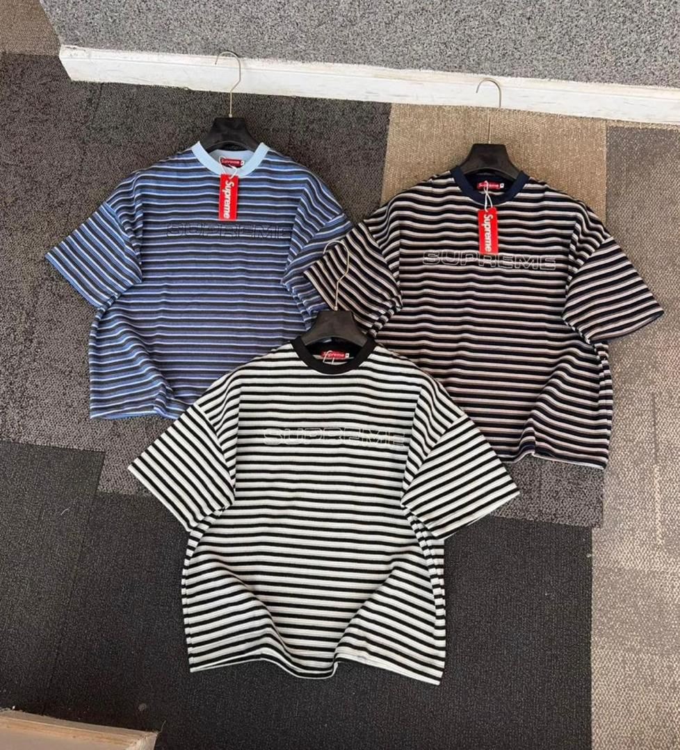 Three Supreme striped t-shirts in blue/white, brown/white, and black/white colorways displayed together.