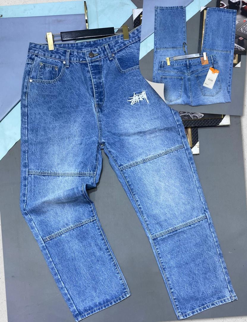 Blue jeans with white Stussy logo on hip and large lower leg cargo pockets, shown with back view.