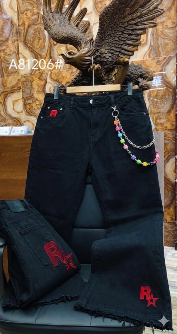 Black jeans with red R star embroidery and multicolored beaded chain on chair display.