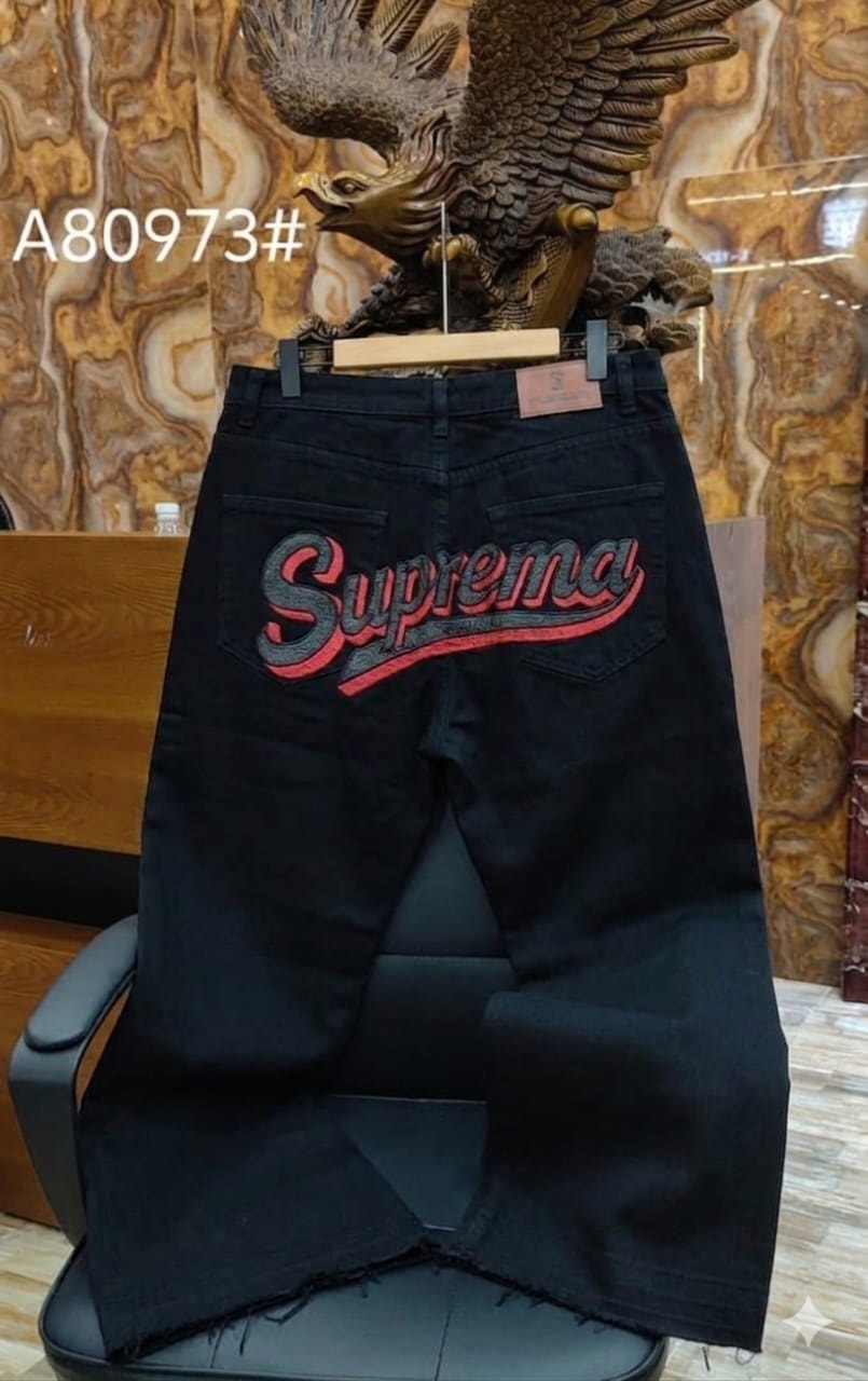Rear view of black jeans with large Suprema embroidery in red and gray.