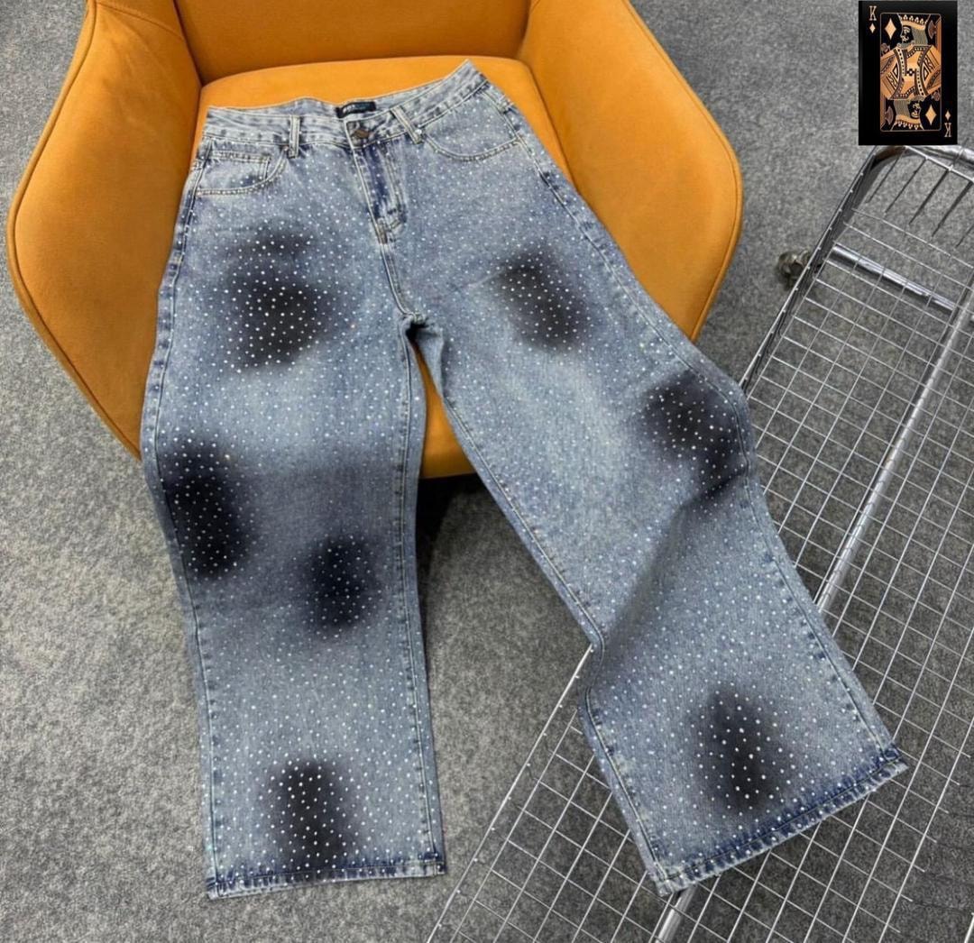 Light blue jeans with white dot pattern and black patches displayed on orange chair.