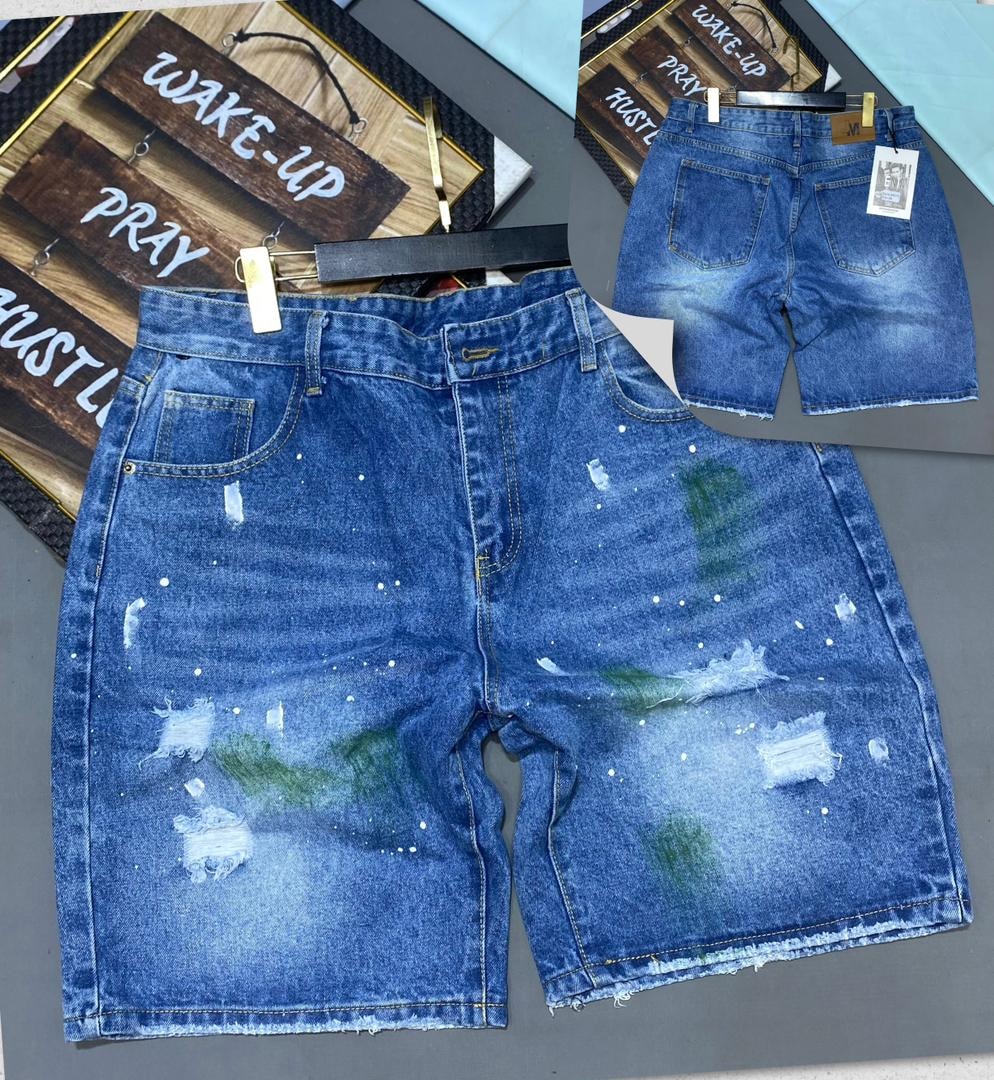 Blue denim jorts with green and white paint splatter, distressing and raw hem, front and back views.