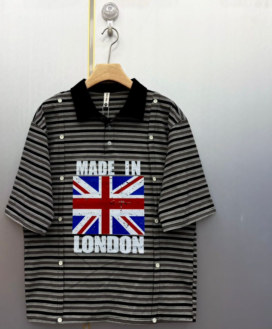 Black striped polo shirt showing Made In London graphic with Union Jack flag.