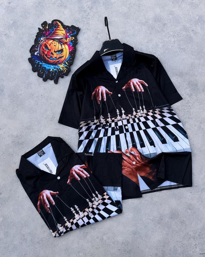 Black short sleeve shirt with puppet hands chess pieces and piano keys graphic.