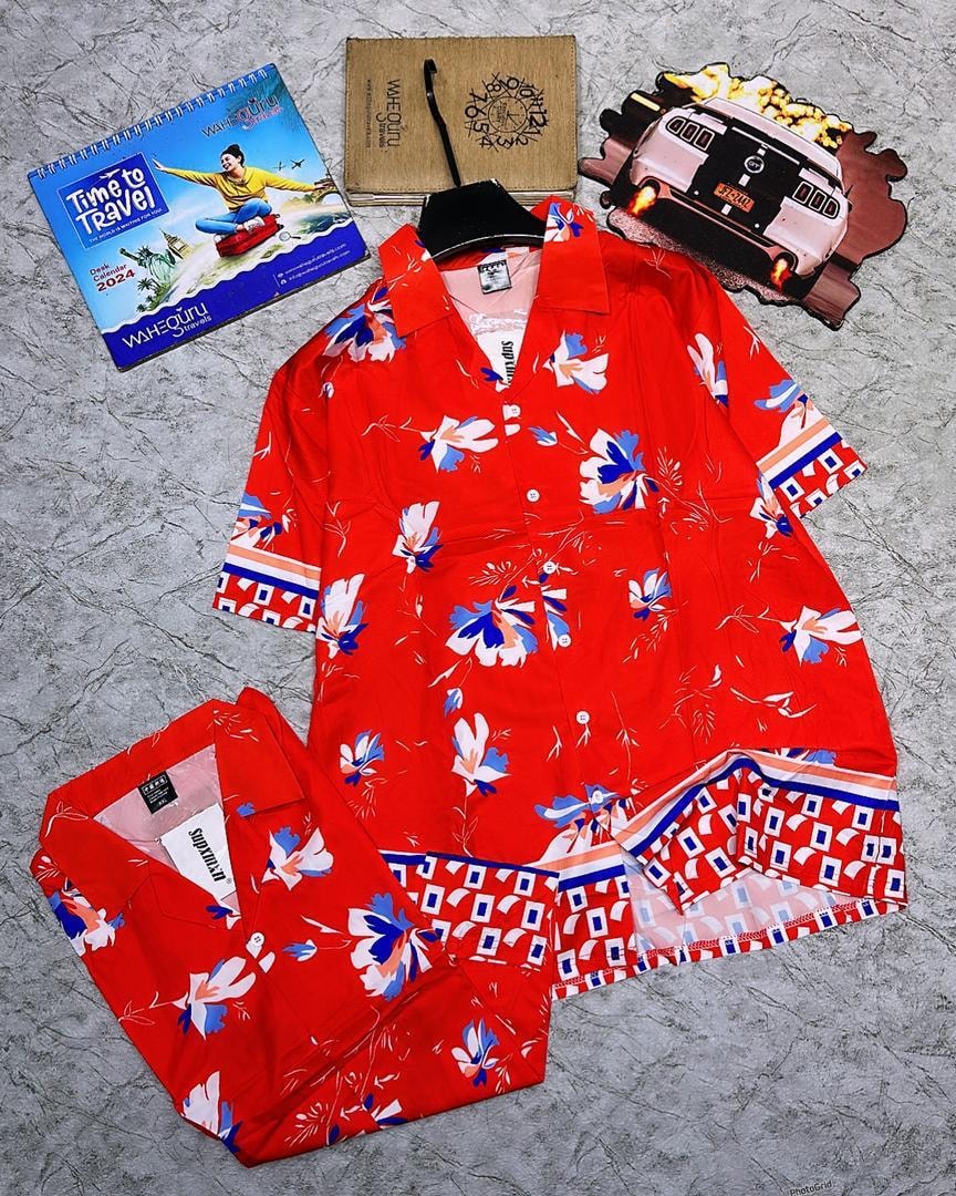 Red short sleeve shirt with blue white and pink floral print and geometric borders.