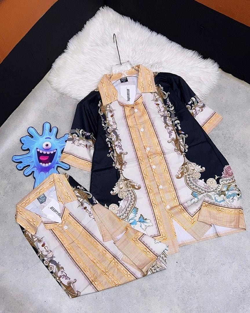 Black short sleeve button-up shirt with gold and white baroque patterns, shown with folded matching bottoms.