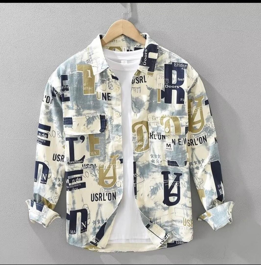 Cream tie-dye shirt with blue and gold text prints hanging on wooden hanger.