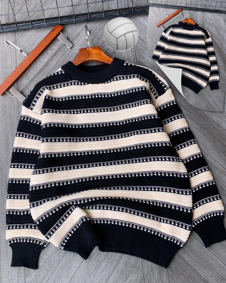 Black and cream striped knitted sweater on wooden hanger with volleyball.