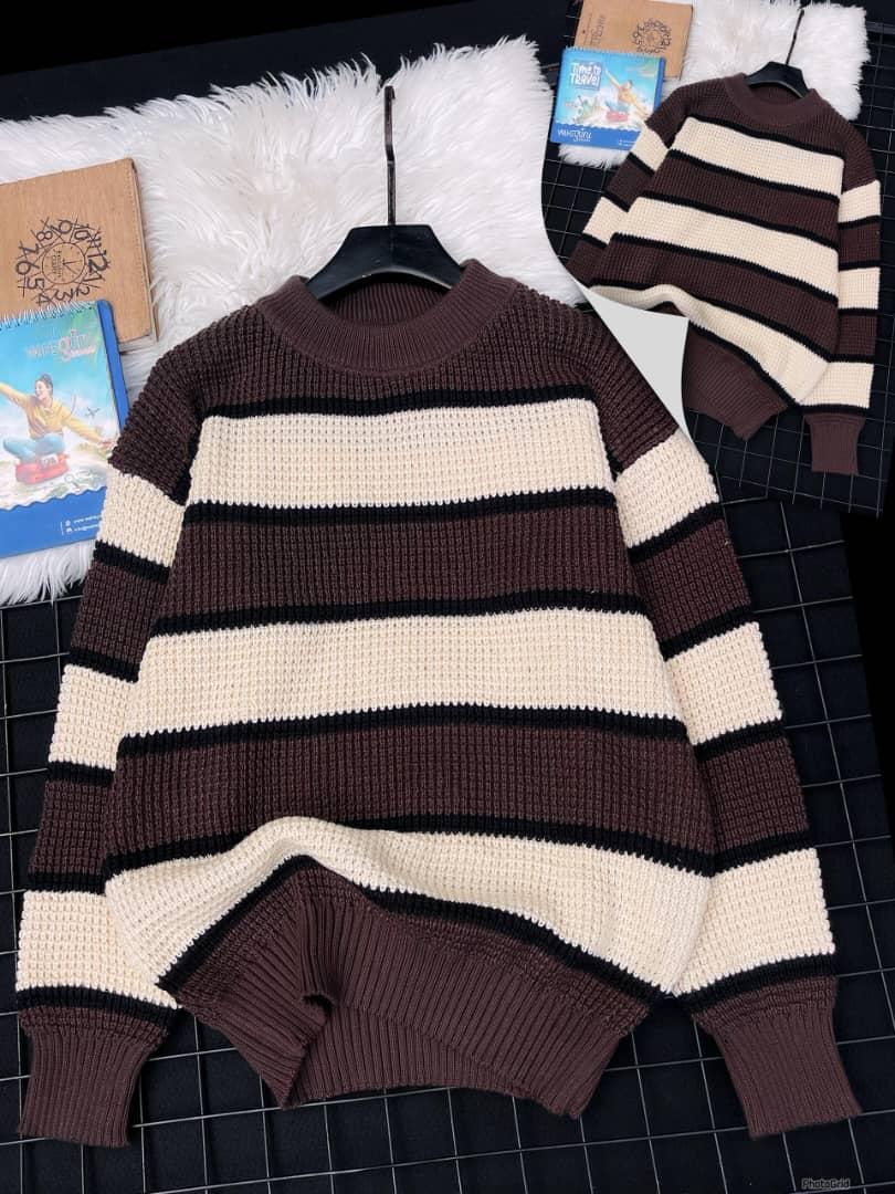 Brown striped knitted sweater with cream and black bands on black grid background.